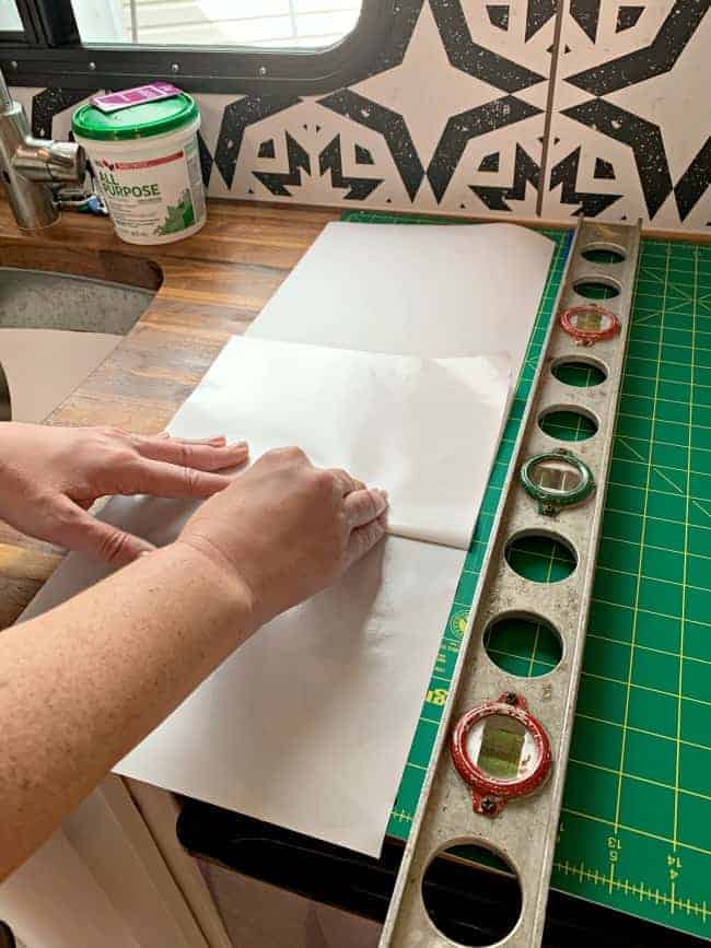 folding up the backing of a panel of removable wallpaper