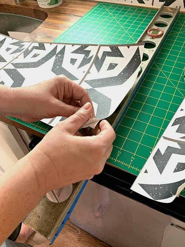 peeling the back off of the removable wallpaper panels for a kitchen backsplash