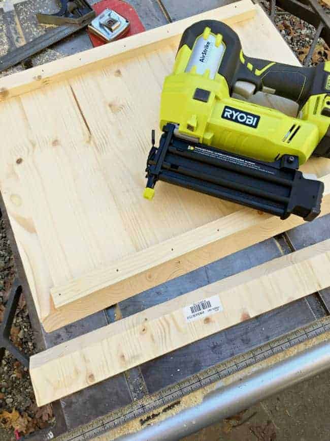 Ryobi brad nailer laying on wood lid for storage ottoman