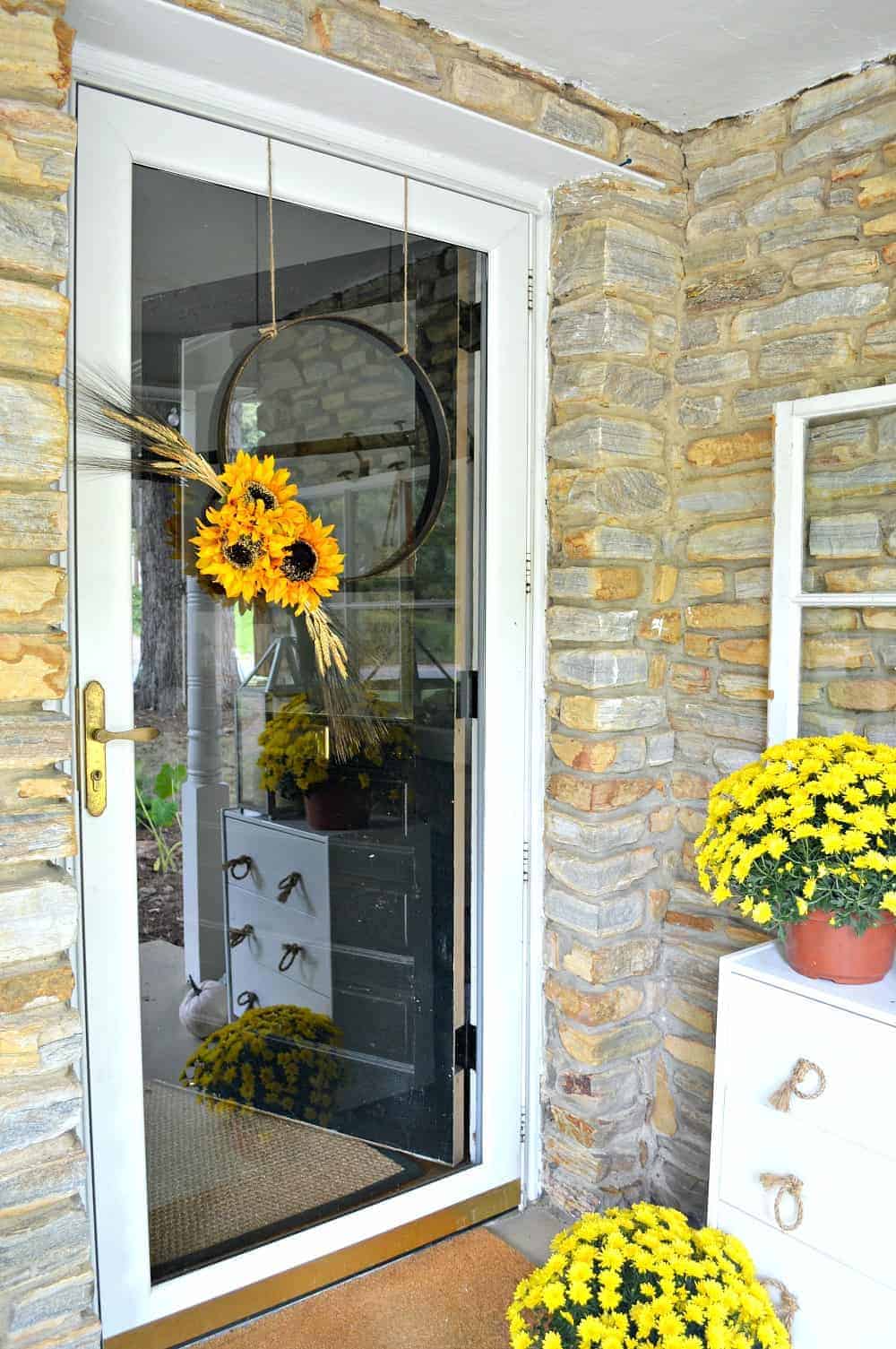 A simple DIY fall front door wreath made with an embroidery hoop hanging on a front door 