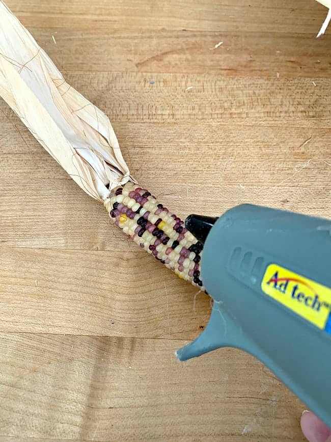 DIY Indian Corn Wreath picture applying hot glue to mini Indian corn cob