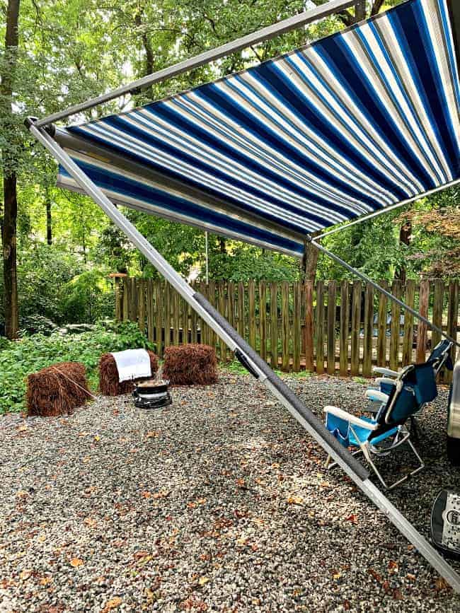 campsite with fire ring and blue striped awning on cargo trailer 