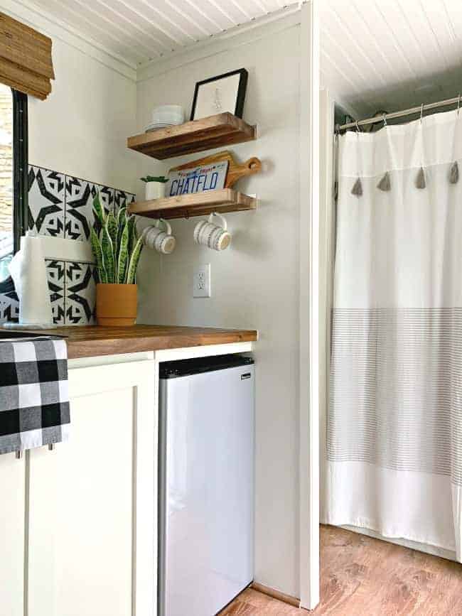 kitchen butcher block shelves and refrigerator in cargo trailer conversion