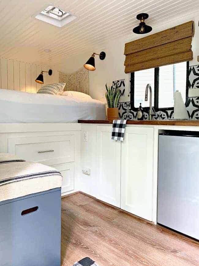 white kitchen, platform bed with storage and DIY stools in cargo trailer conversion