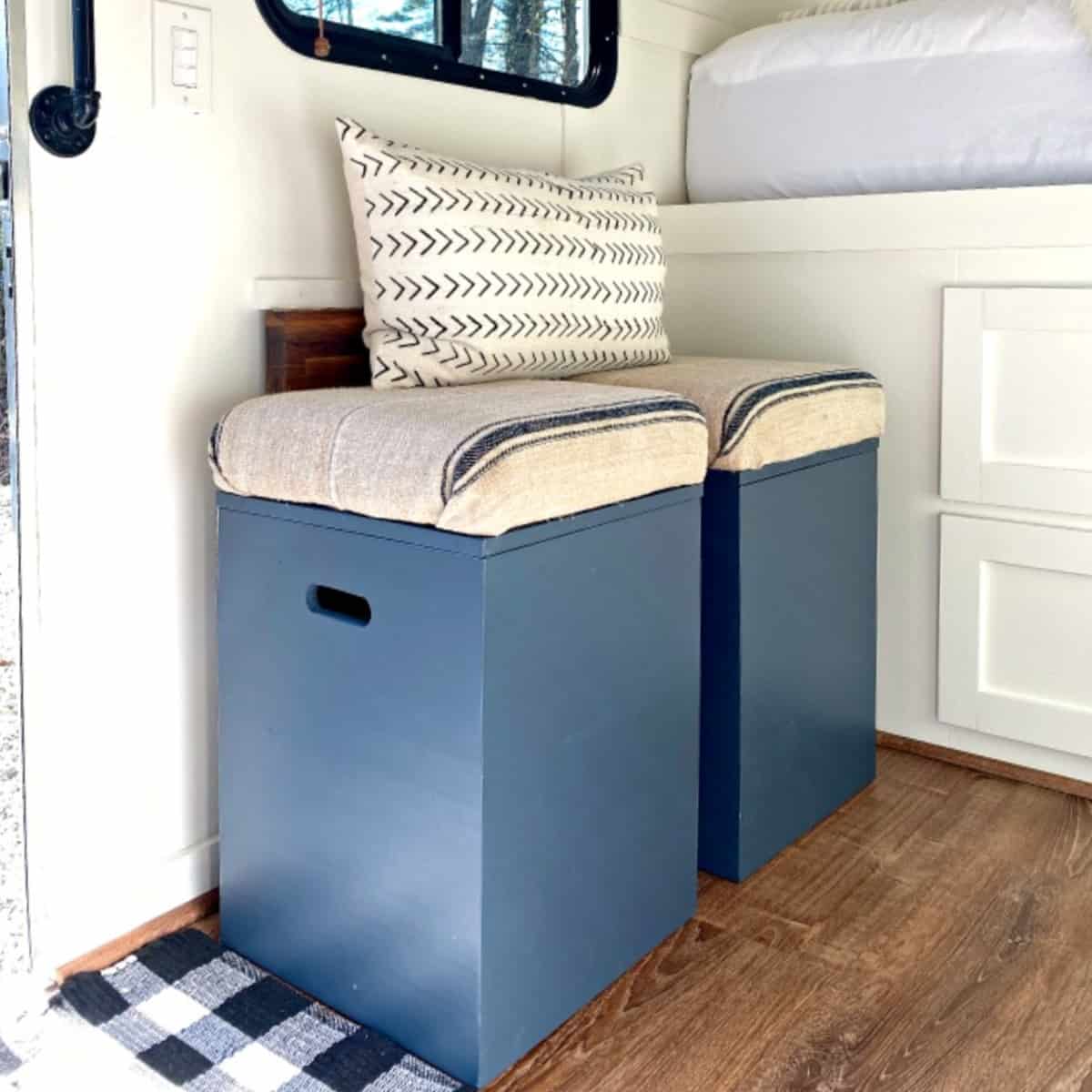 2 navy DIY storage ottomans lined up against wall in RV