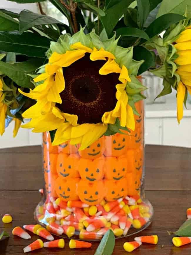 fall halloween candy centerpiece with sunflowers and foliage in the middle of a table