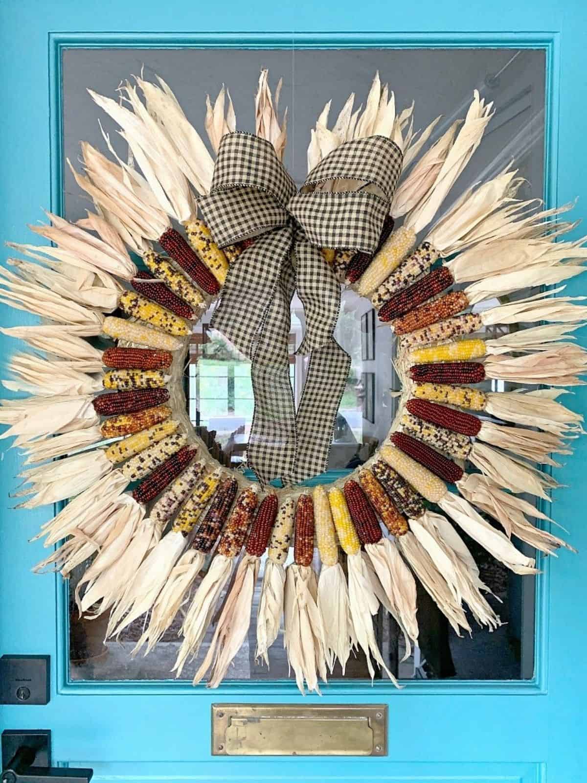 mini Indian corn wreath hanging on turquoise front door