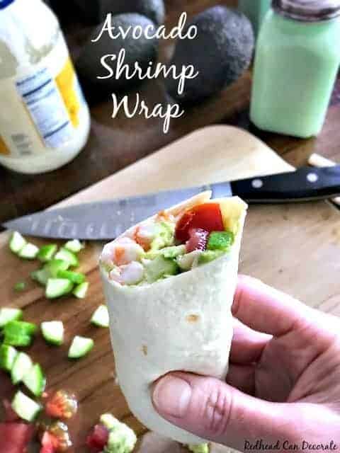 holding an avocado shrimp wrap cut in half