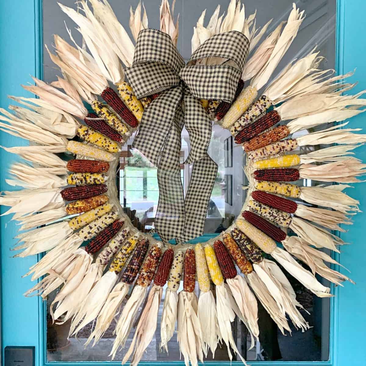 mini corn wreath hanging on turquoise front door