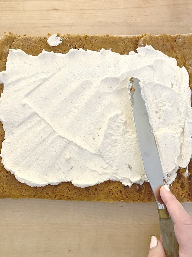 spreading cream filling on pumpkin cake