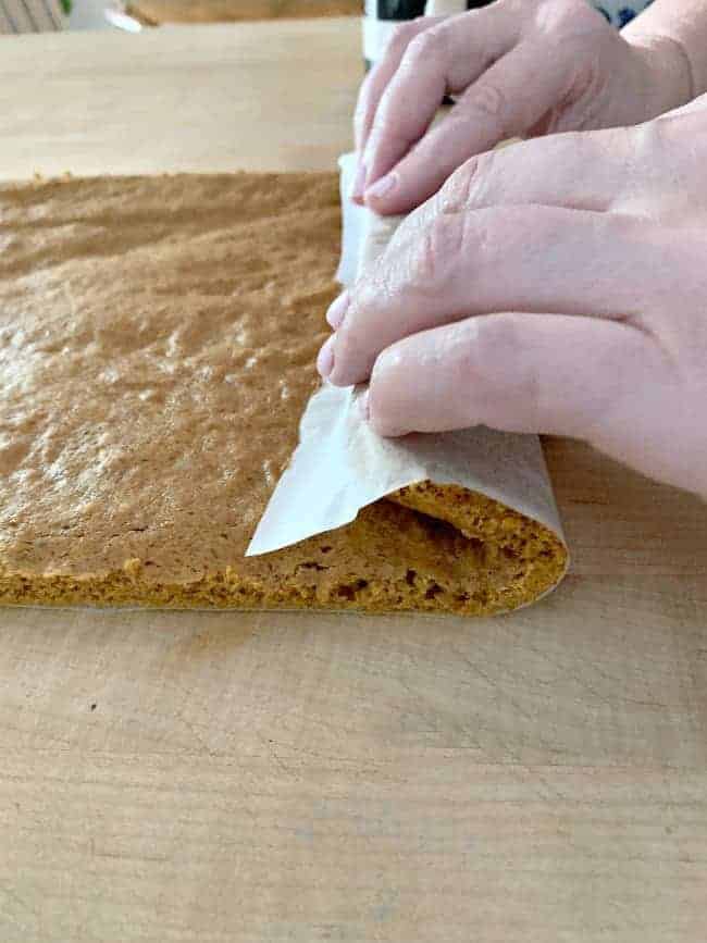 rolling hot pumpkin roll cake on butcher block