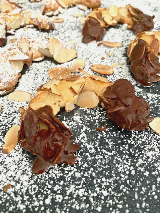 chocolate dipped almond horn cookies on powdered sugar board