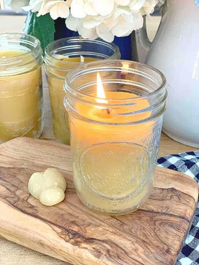 lit beeswax mason jar candle on cutting board