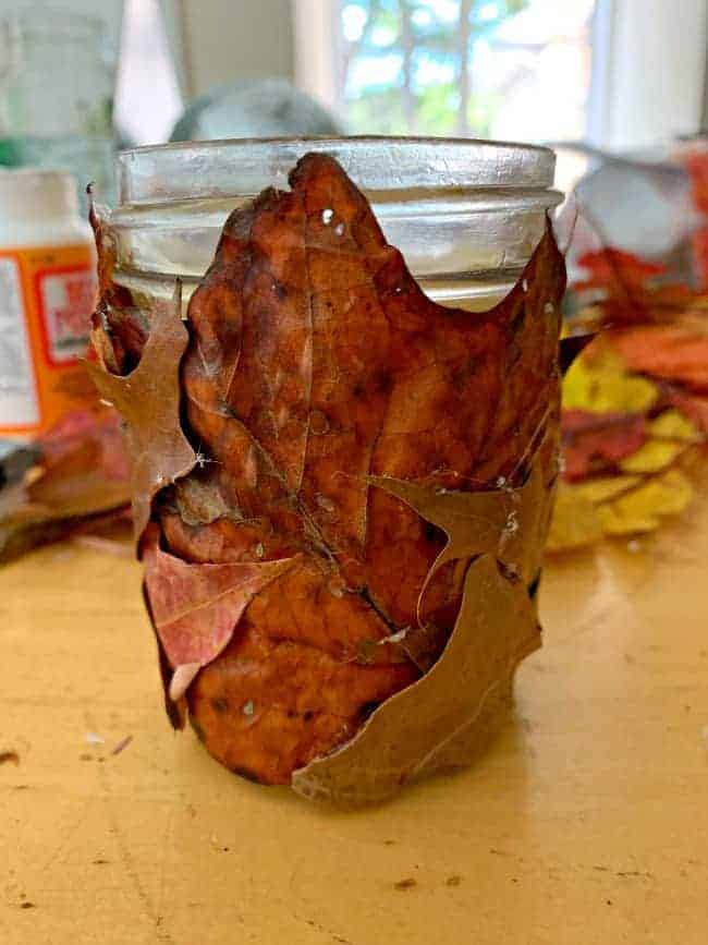 fall leaves glued onto a mason jar candle