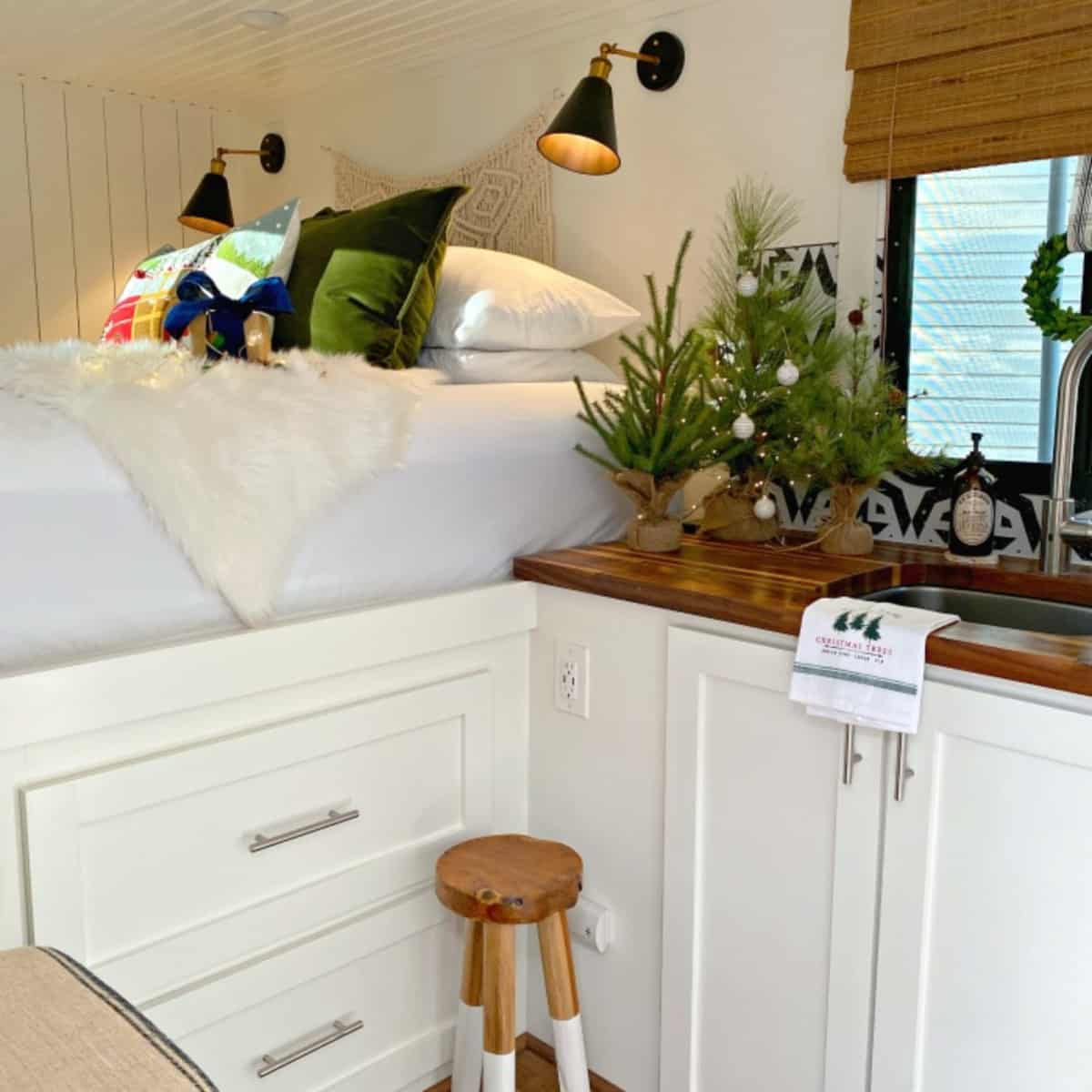 faux Christmas trees on butcher block counter and Christmas pillows on RV bed