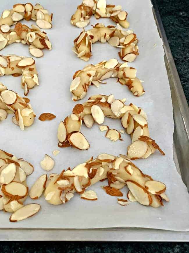 almond horn cookie dough formed into cookies on cookie sheet