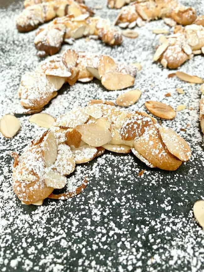 almond horn cookies on black board with powdered sugar sprinkled on top