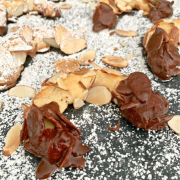 almond horn cookie dipped in chocolate and dusted with powdered sugar