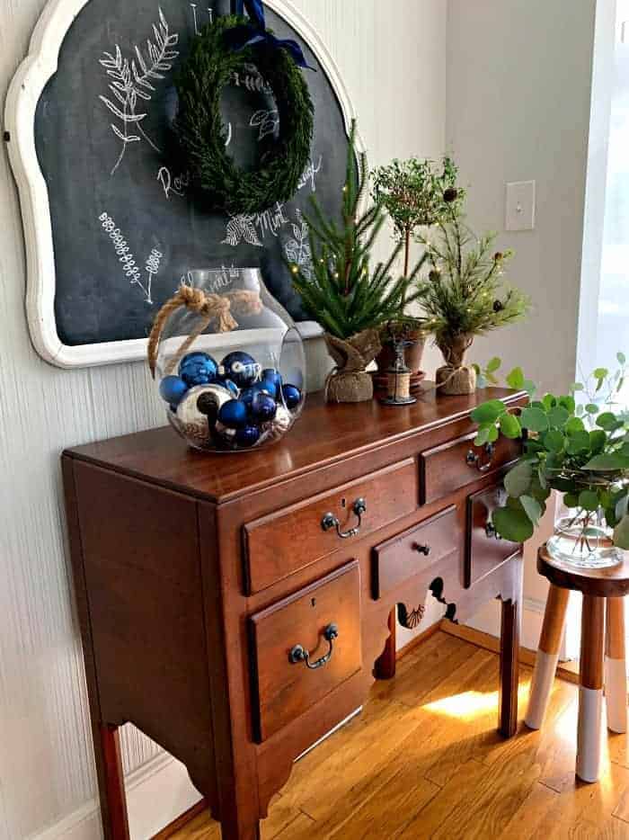 dining room buffet with glass jar full of ornaments and grouping of faux mini Christmas trees