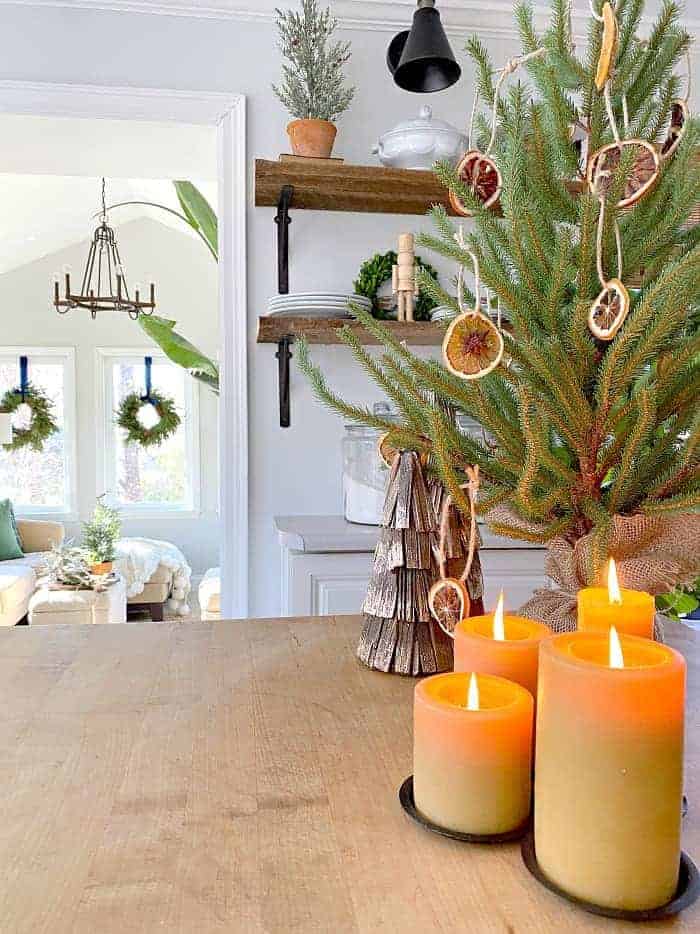 view of faux Christmas tree with dried orange ornaments and grouping of beeswax candles