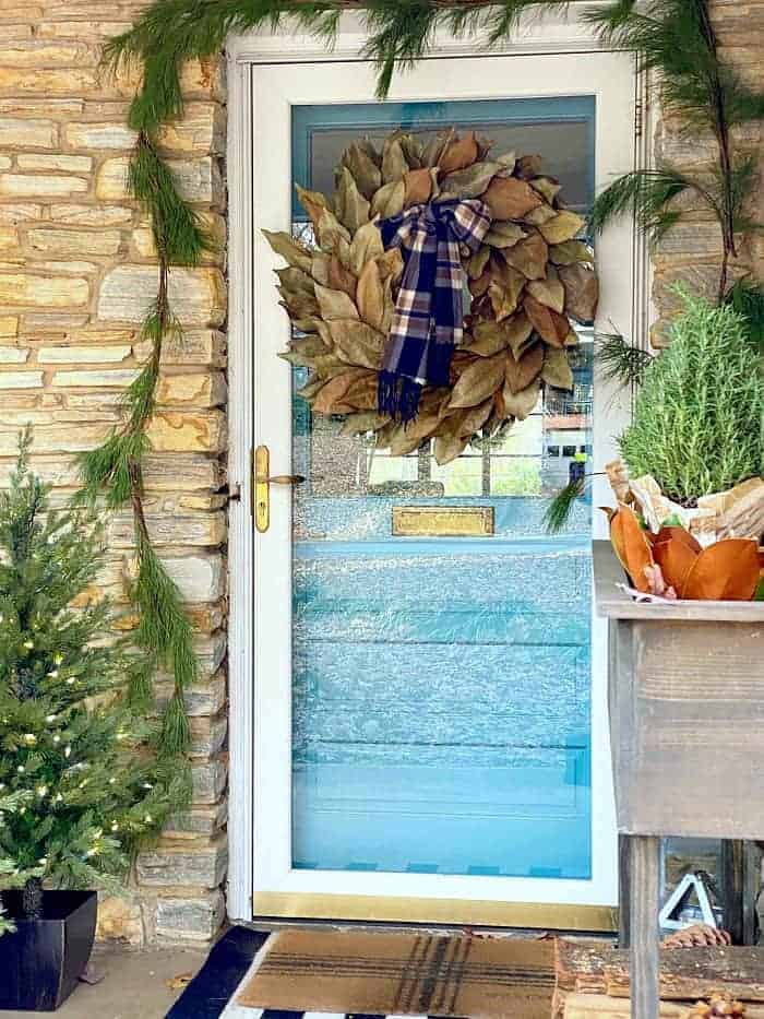 view of front door decorated for Christmas with magnolia leaf wreath