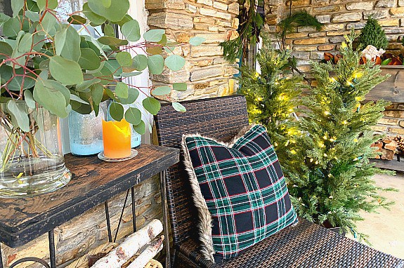 woven chair with black and green pillow on front porch decorated for Christmas