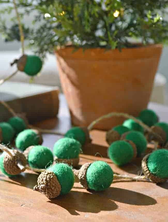 felted green acorn garland on cutting board 