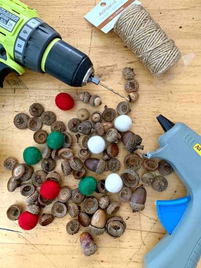 supplies to make felted acorn garland including felted wool balls, acorns, drill, hot glue gun and twine