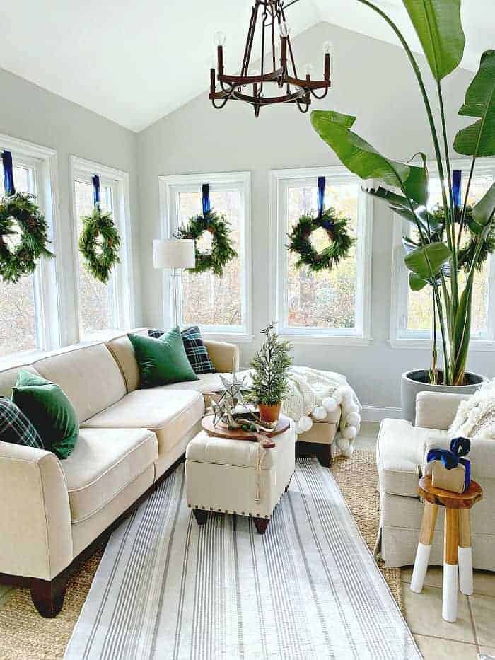 sunroom decorated for Christmas with wreaths hanging in windows