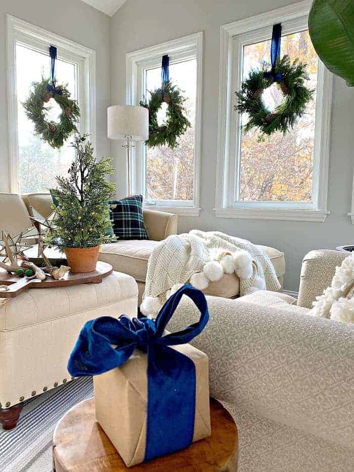 navy blue Christmas decor and wreaths hanging on windows in sunroom