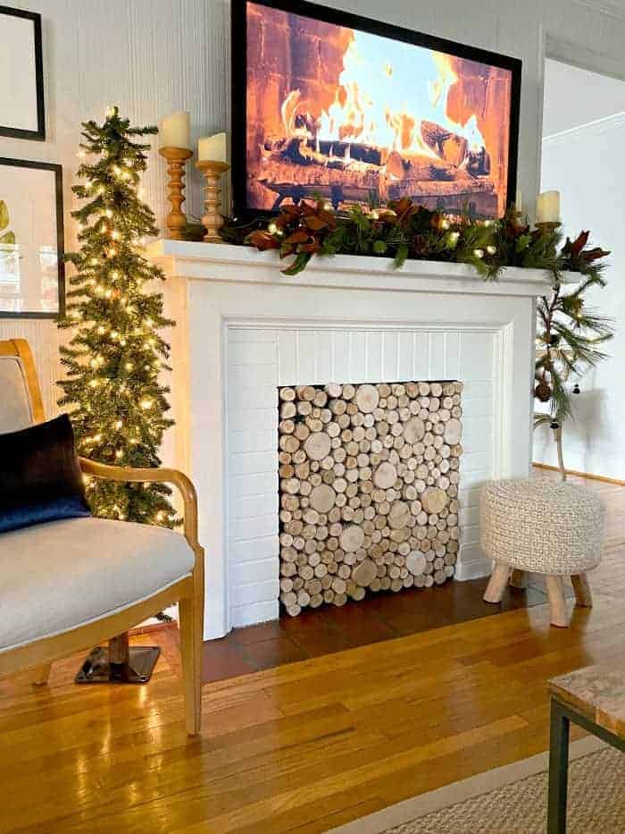 view of Christmas tree and fireplace decorated for Christmas with garland and a fire burning on the tv screen