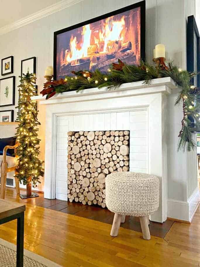 view of Christmas tree and fireplace decorated for Christmas with garland and a fire burning on the tv screen