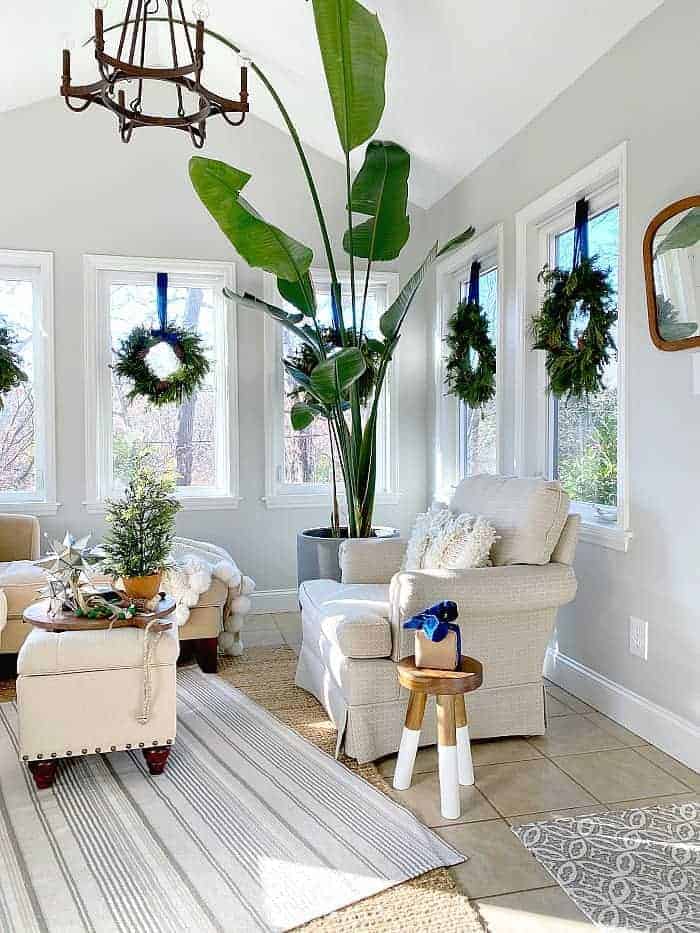 sunroom decorated for Christmas with wreaths hanging in windows