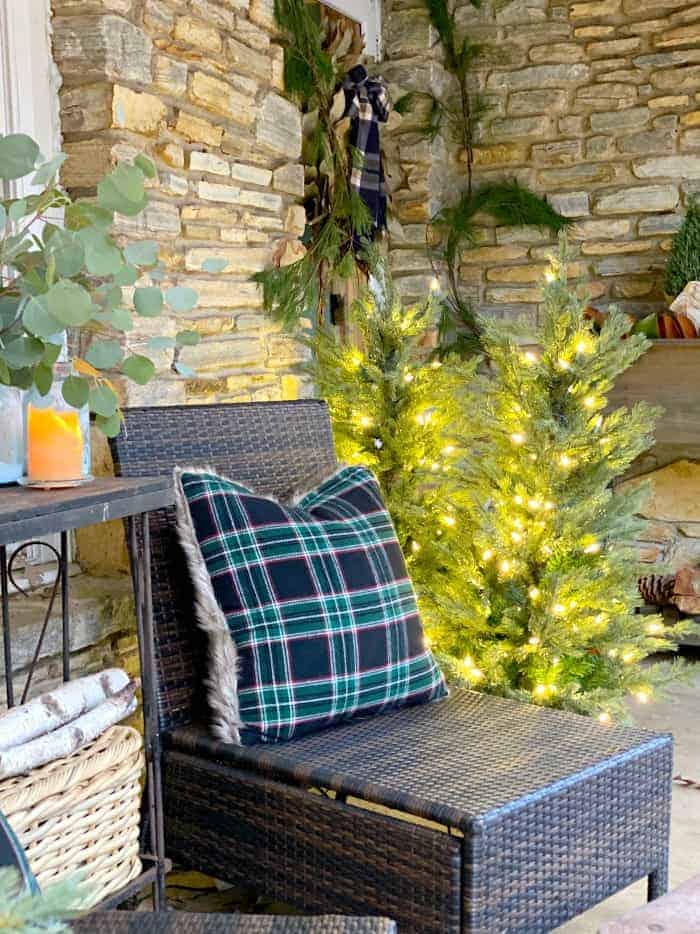 woven chair with black and green pillow on front porch decorated for Christmas