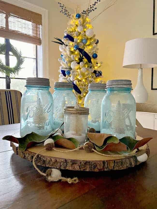 DIY mason jar Christmas centerpiece on dining table with tree in background