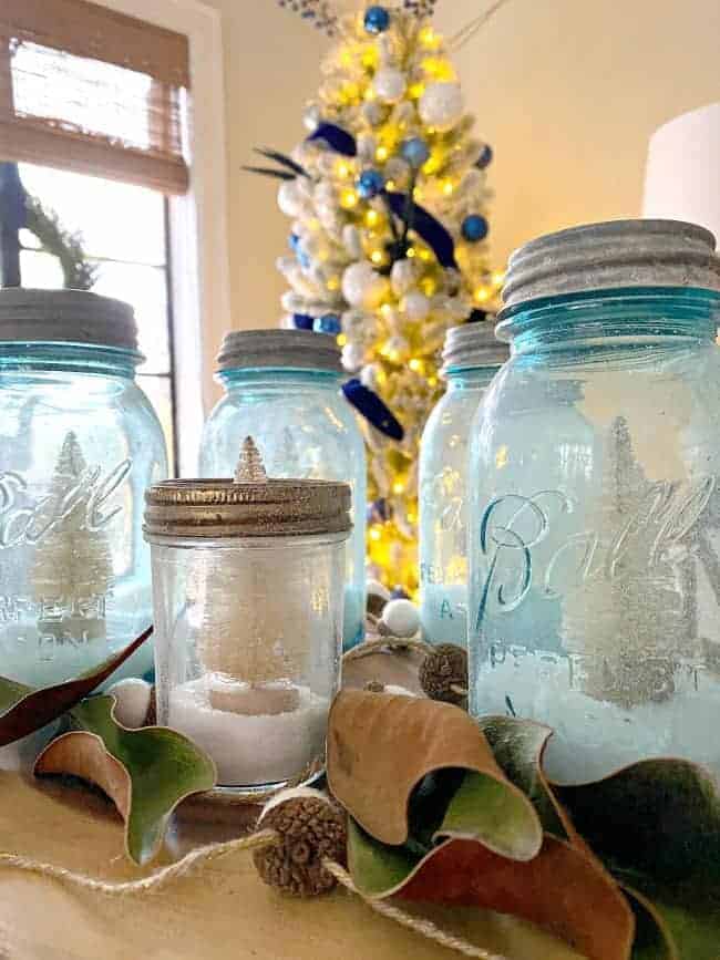 closeup of DIY mason jar Christmas centerpiece on dining table with tree in background
