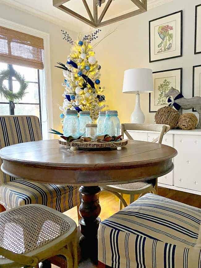 view of cottage dining room with DIY mason jar Christmas centerpiece on dining table with tree in background