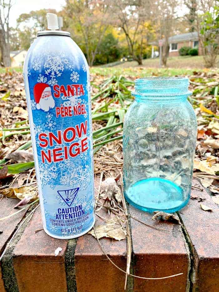 blue mason jar and can of faux snow on brick wall