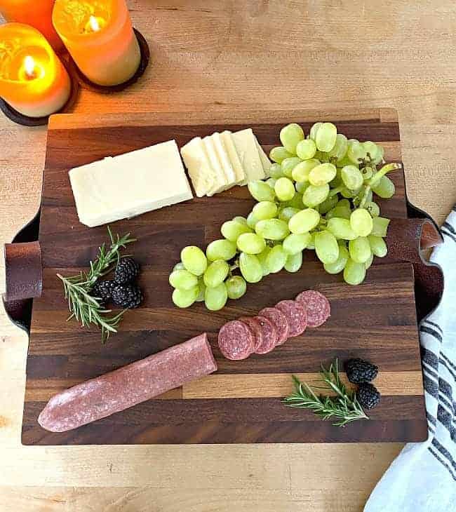 sliced meat and cheese, a bunch of grapes and blackberries on top of DIY butcher block cutting board