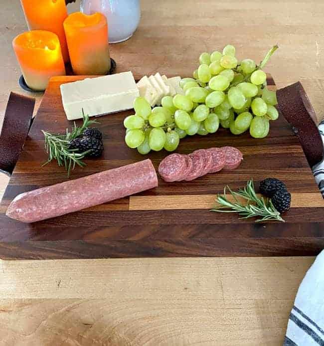 sliced meat and cheese, a bunch of grapes and blackberries on top of DIY butcher block cutting board
