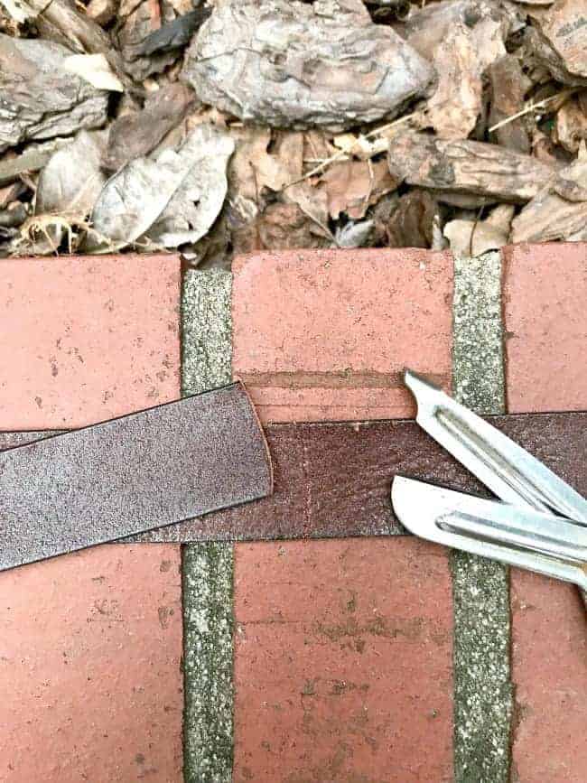scissors and leather belt on brick wall