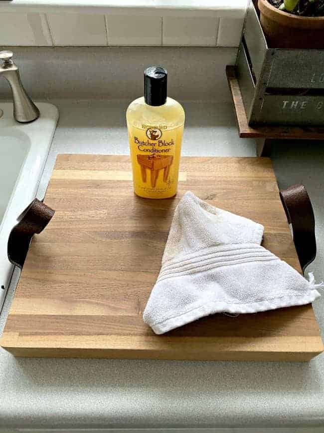 wood conditioner and clean cloth on top of butcher block cutting board