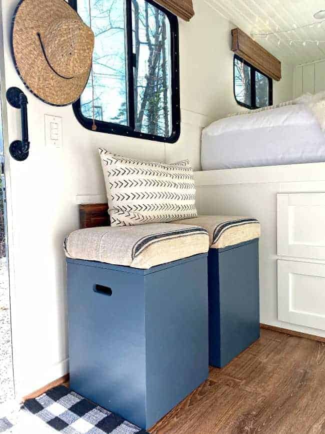 2 navy DIY storage ottomans lined up against a wall in an RV