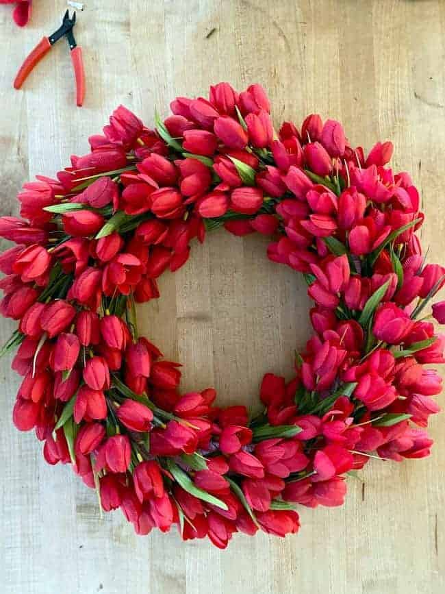 overhead view of faux red tulip wreath on butcher block