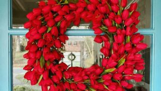 faux red tulip wreath hanging on turquoise painted front door