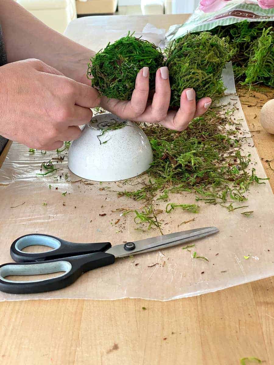 holding 2 DIY moss covered Easter eggs in a hand