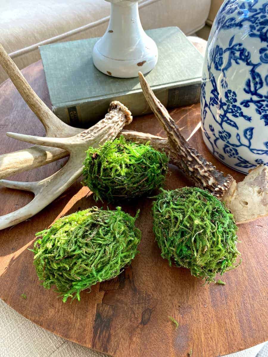 3 DIY moss covered Easter eggs on a wood cutting board with antlers