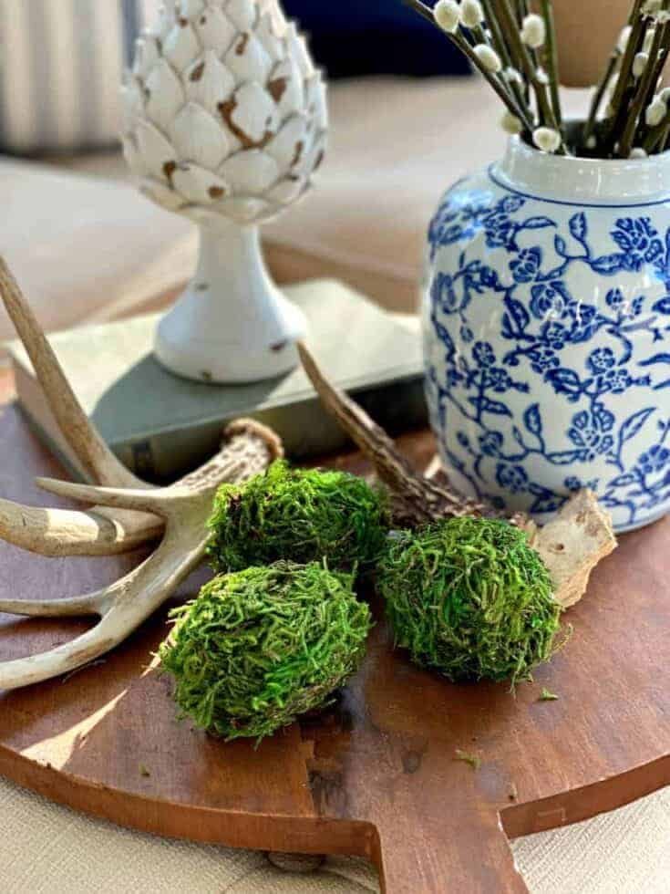 3 DIY moss covered Easter eggs on a wood cutting board with antlers