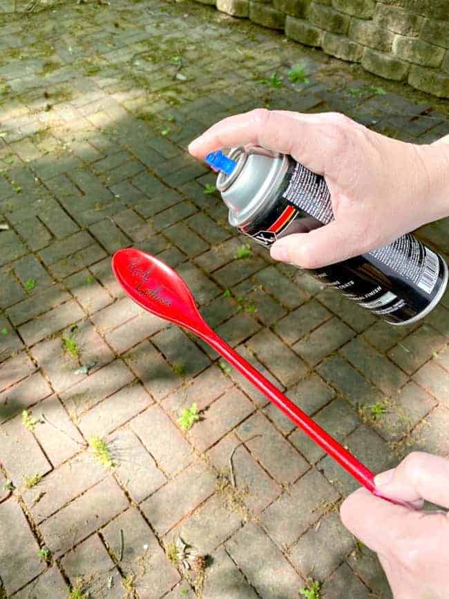 spraying poly on red plastic veggie garden marker