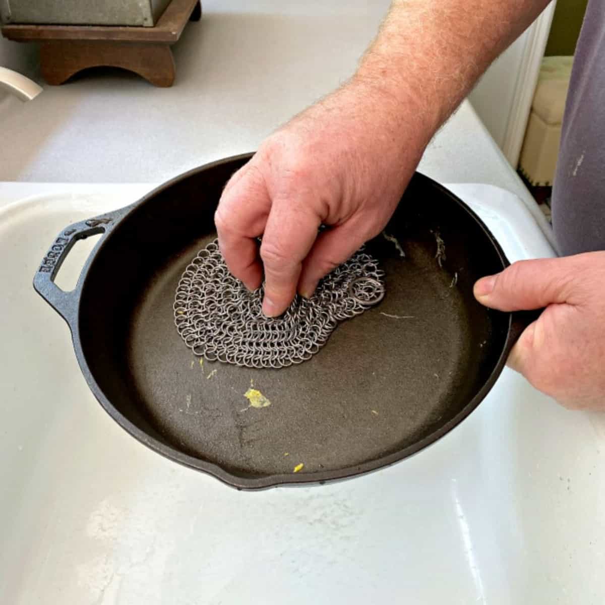 scrubbing a dirty cast iron pan with a scrubber